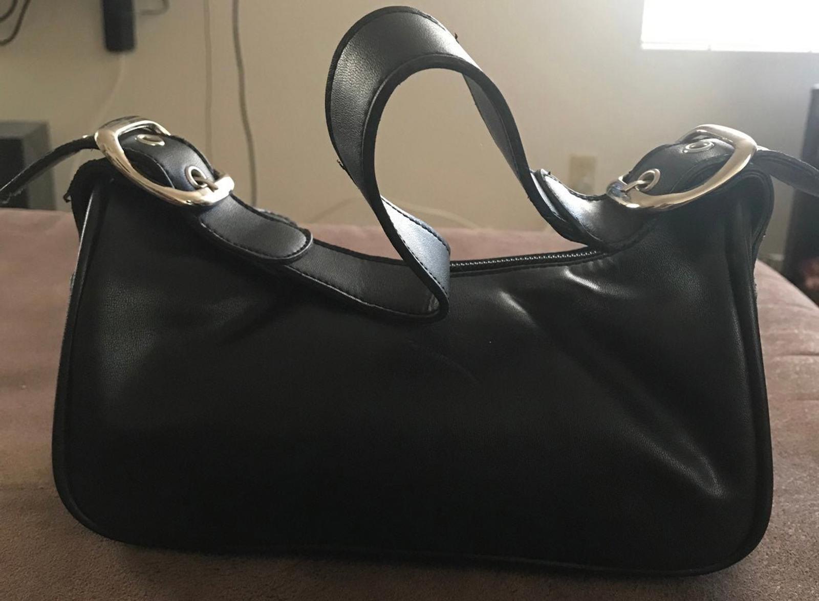 Black leather hobo-style purse with top zipper and adjustable buckle shoulder strap