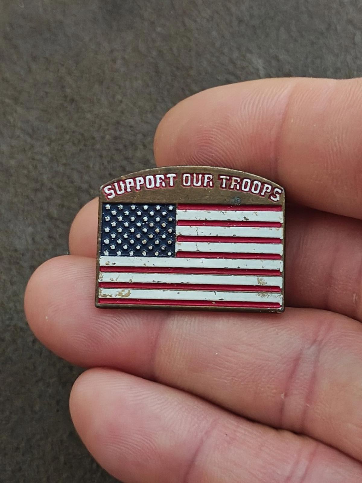 Gold-tone enamel pin with U.S. flag stars panel and red-white stripes; “Support Our Troops”