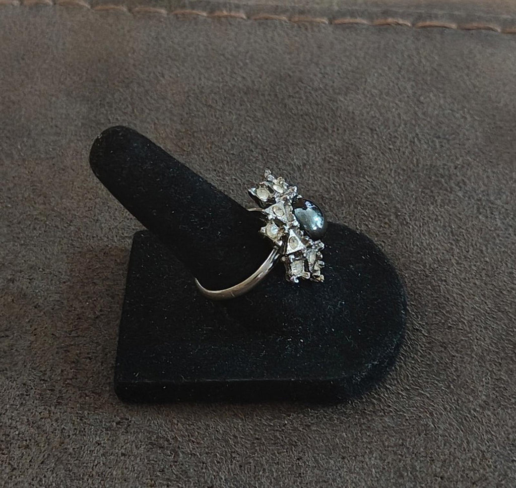 Vintage side view of silver tone snowflake ring with dark hematite center and clear stones