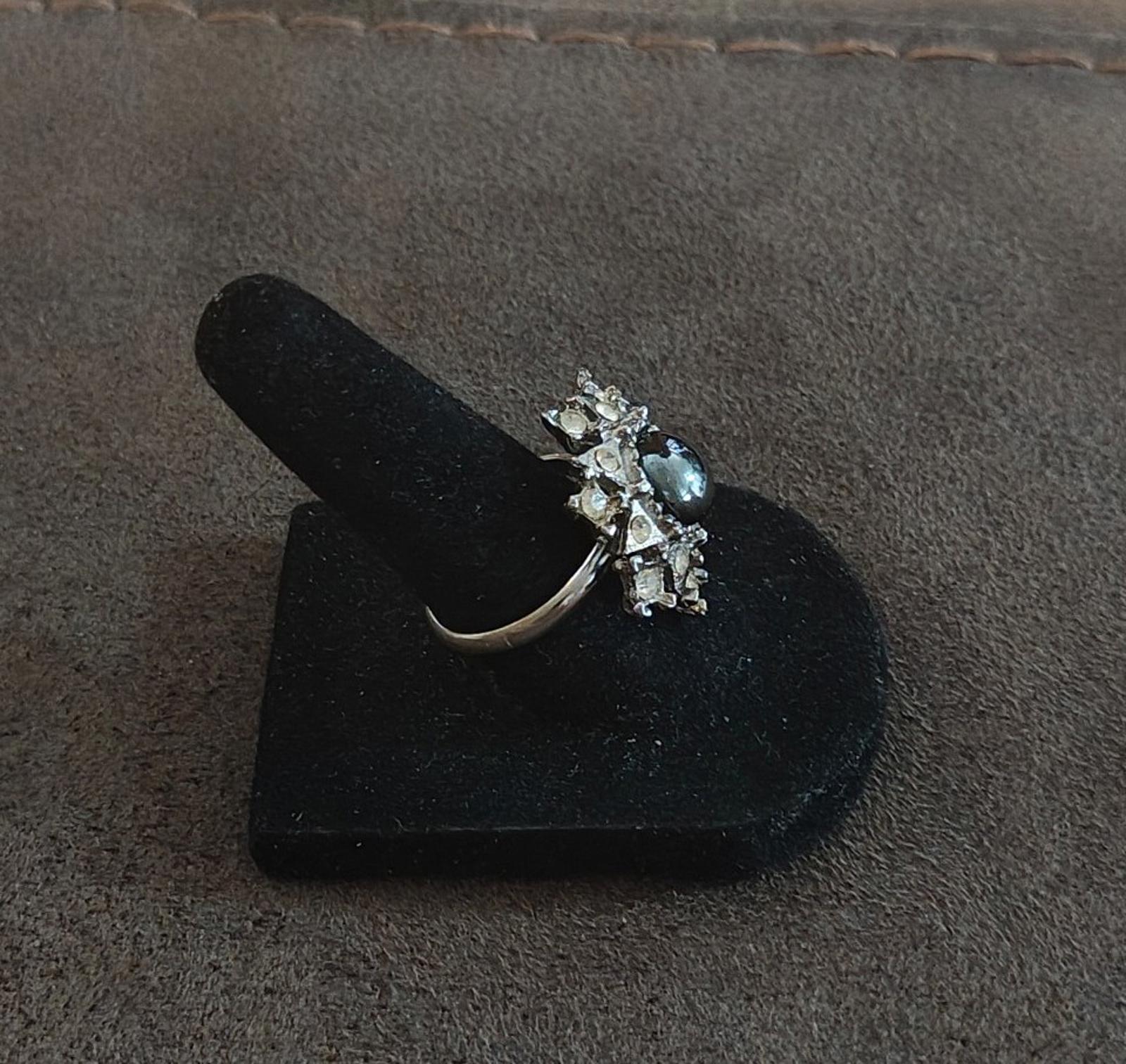 Vintage side view of silver tone snowflake ring with dark hematite center and clear stones