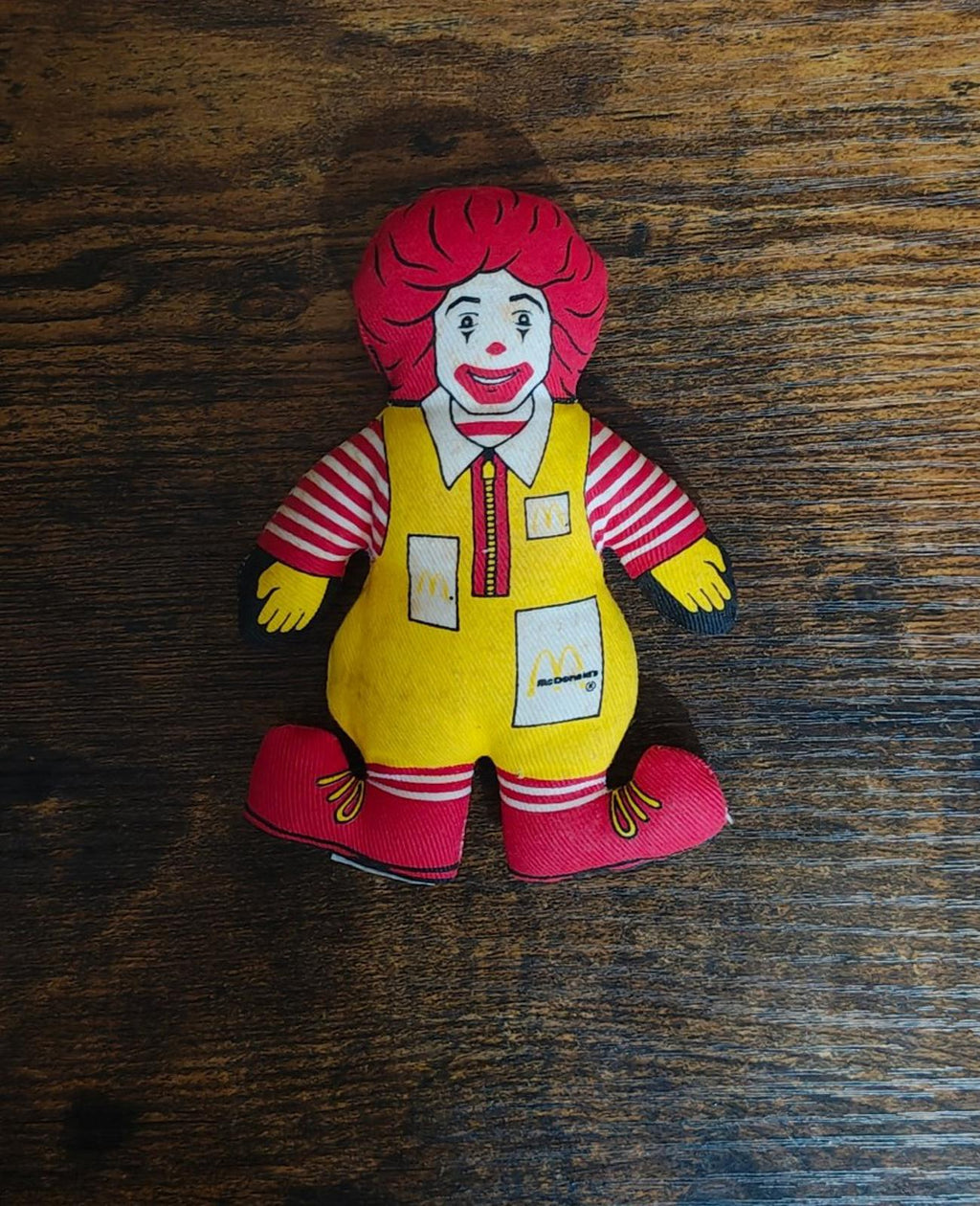 Ronald McDonald plush doll, smiling face, red hair, striped shirt, yellow apron
