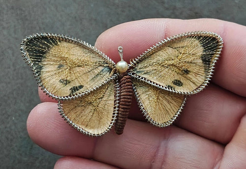 Butterfly brooch pin with gold-tone wire wings, pearl center bead, and dark red body