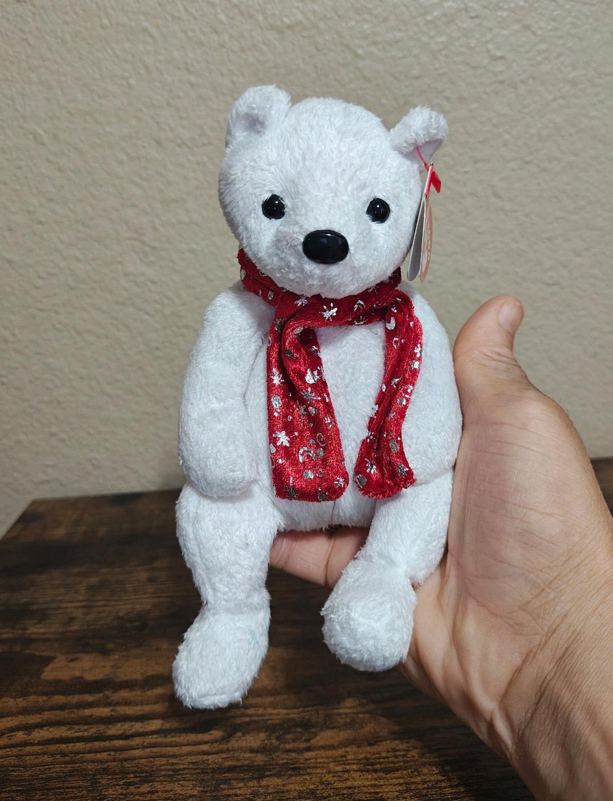 White bear plush with red holiday scarf, beanbag-style, held in hand