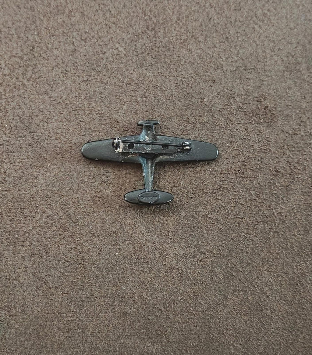 Small airplane brooch with dark metal body and silver-toned details