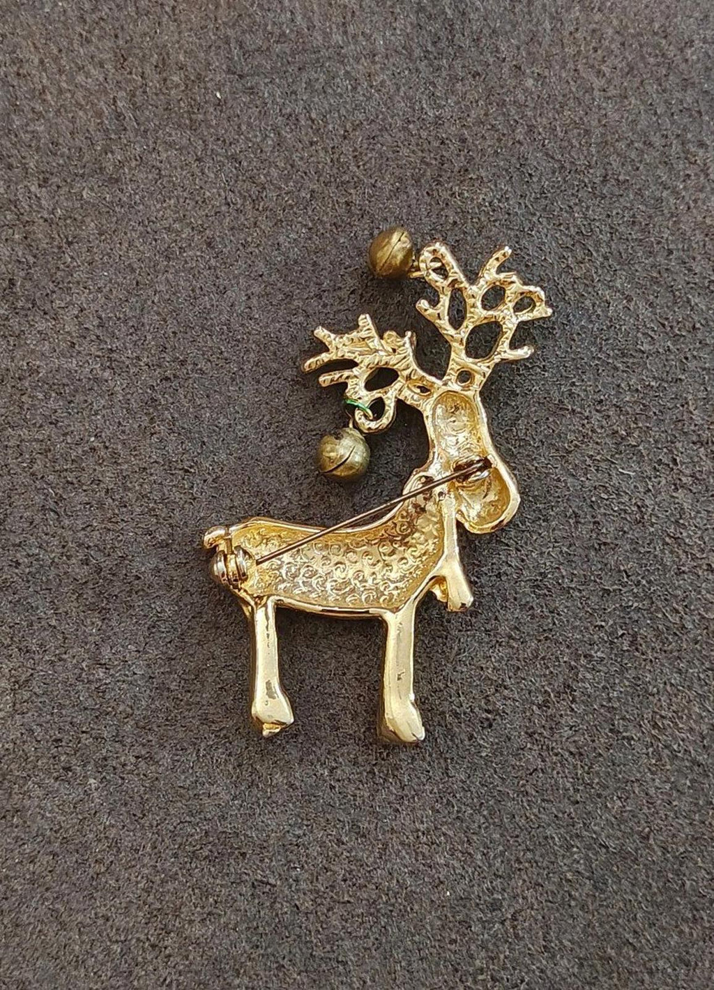 Gold-tone reindeer pin brooch with raised antlers and bell accents.