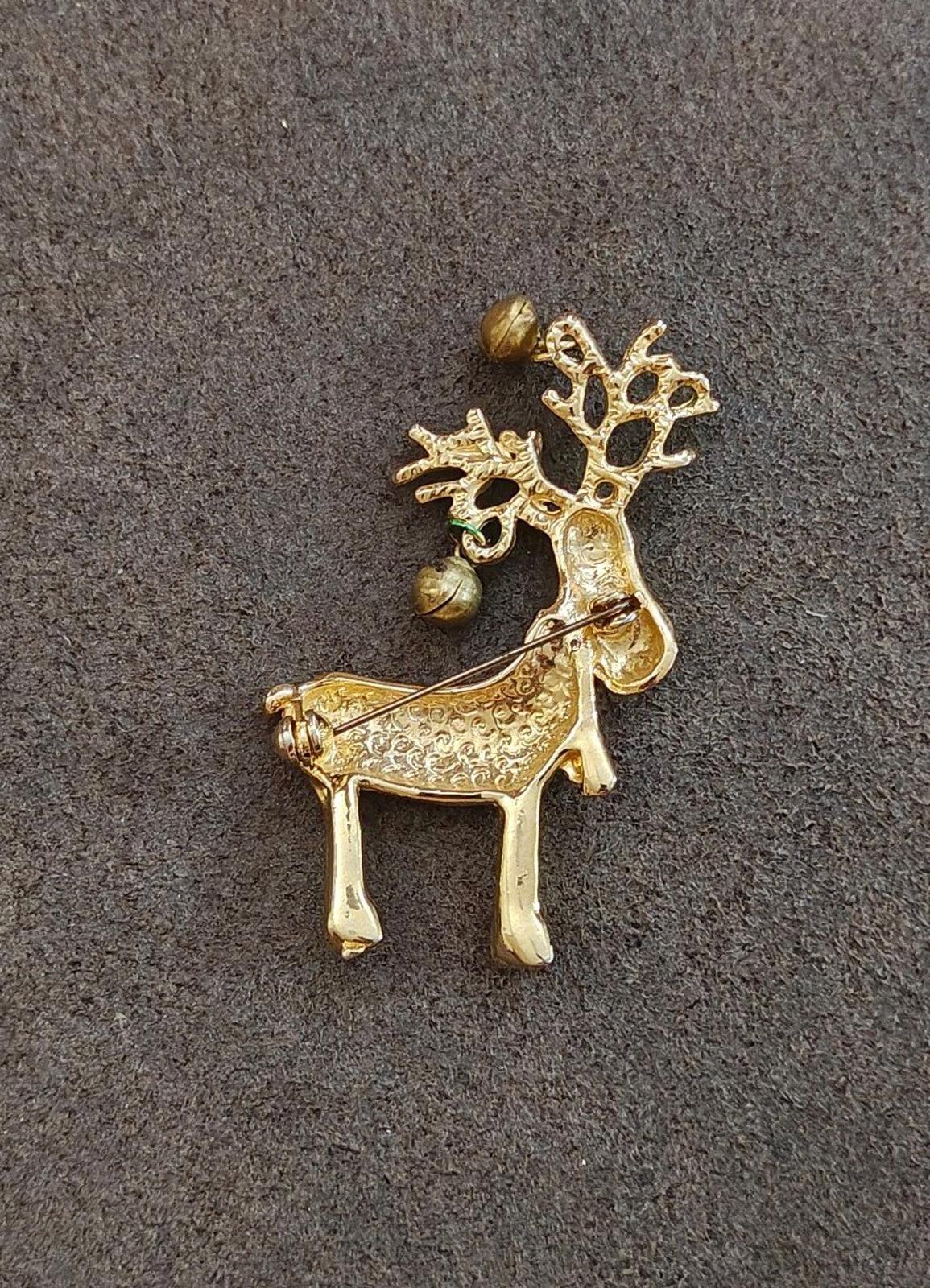 Gold-tone reindeer pin brooch with raised antlers and bell accents.
