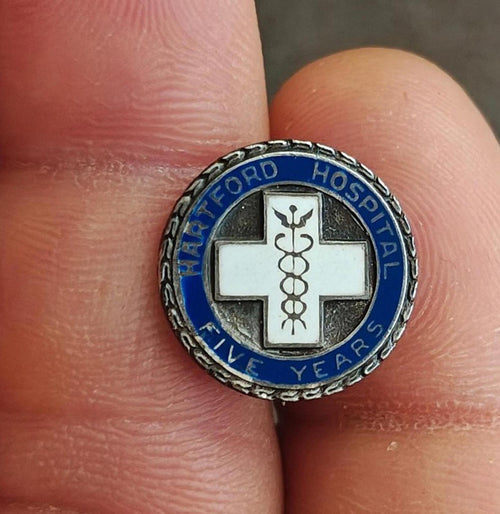 Round sterling silver hospital service enamel pin with blue ring, white cross, caduceus