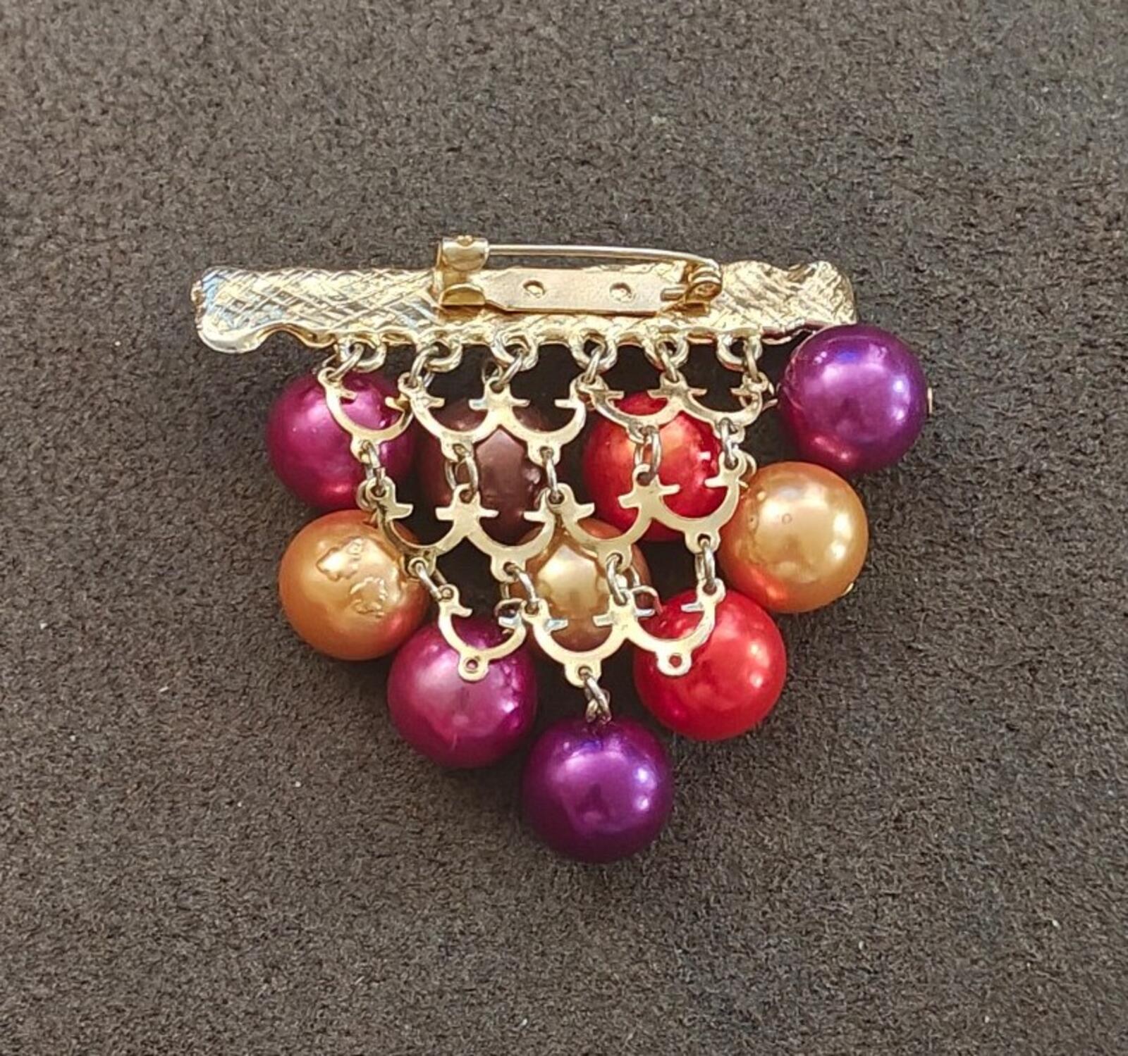 Gold-tone chandelier brooch with dangling purple, red, and gold beads from bar