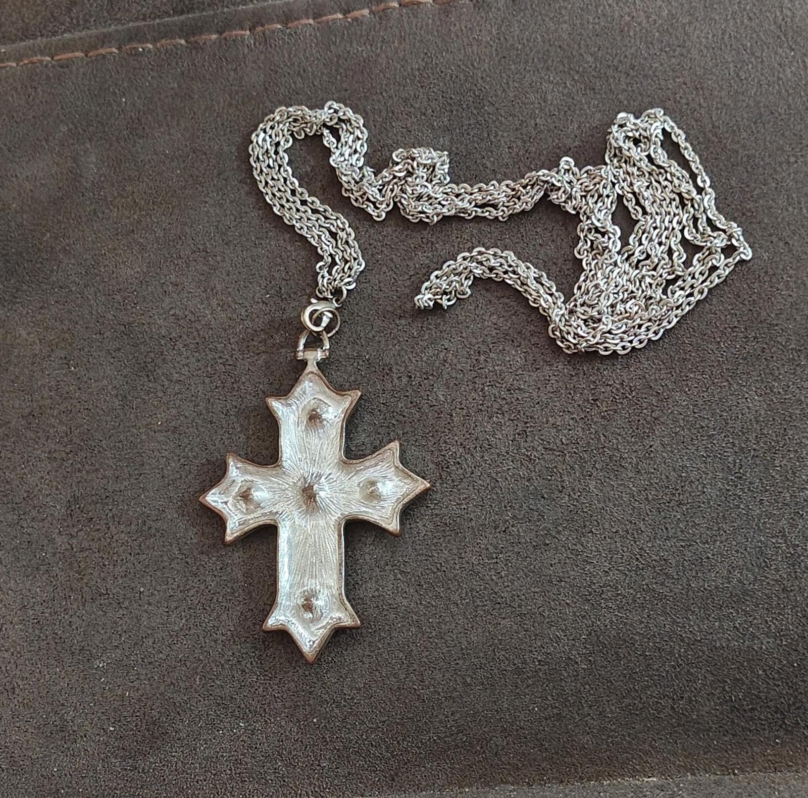 Silver tone cross pendant necklace with textured silver finish and small red stone details