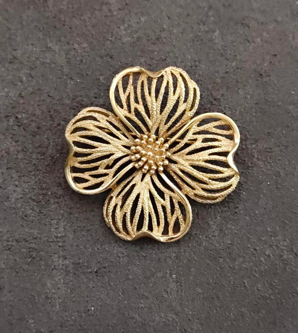 Gold-tone dogwood flower brooch with textured leaf-like petals and beaded center