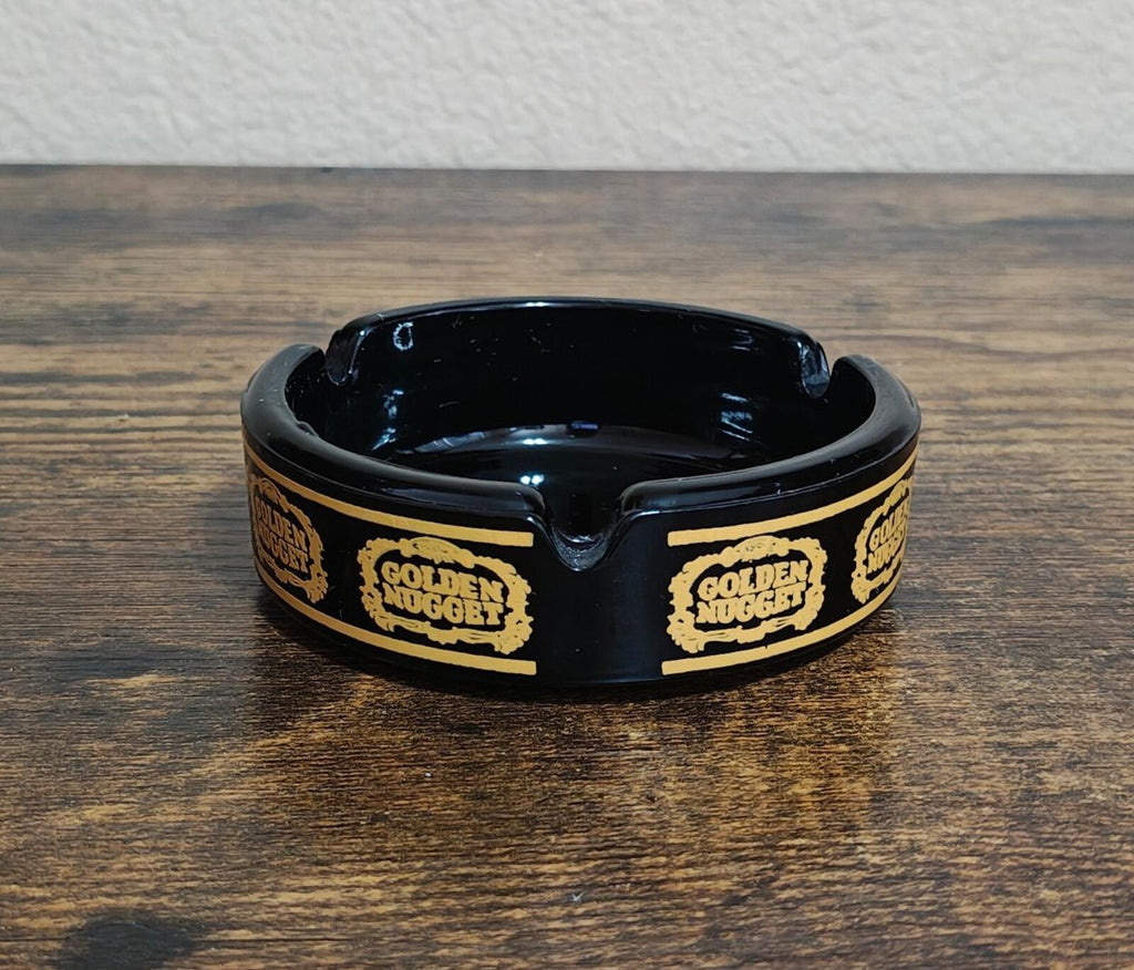 Vintage black ceramic ashtray with shiny interior and gold Golden Nugget logo band