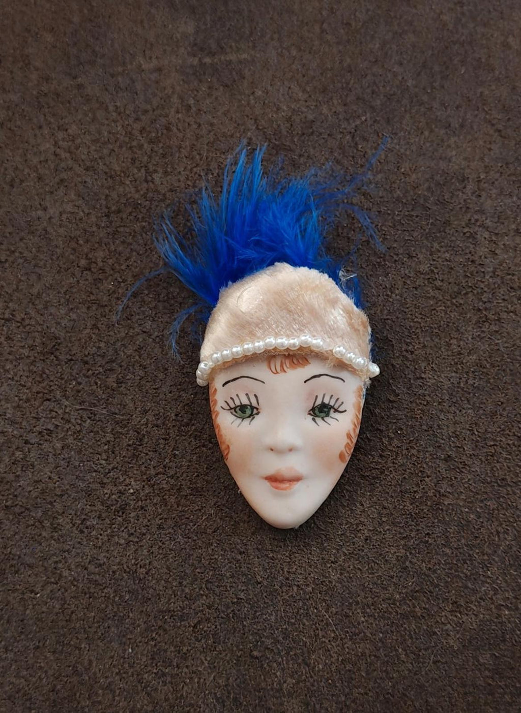 Doll face pin brooch with blue feather and cream beaded headband