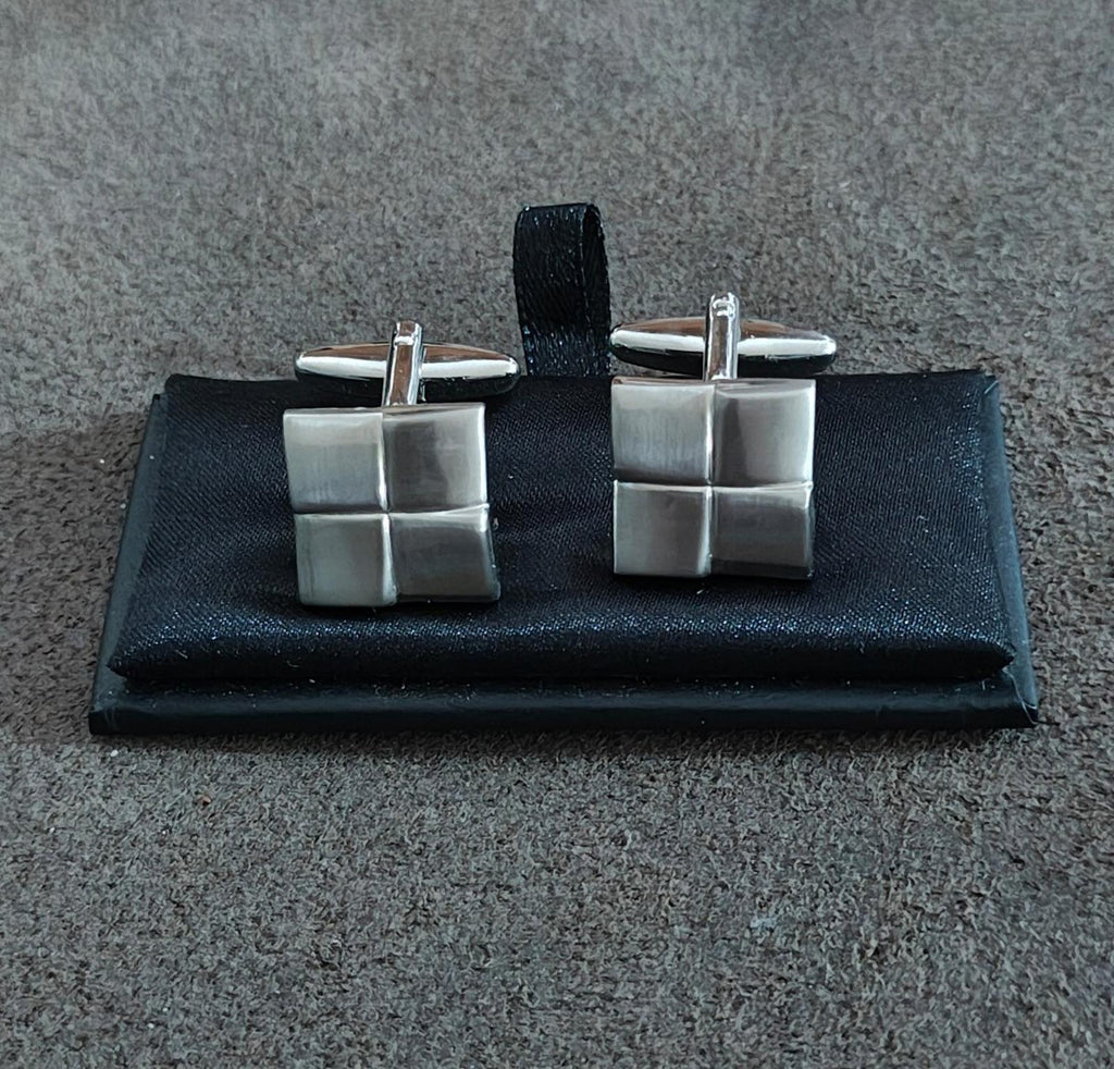 Pair of brushed silver square cuff links with geometric grid styling on black card