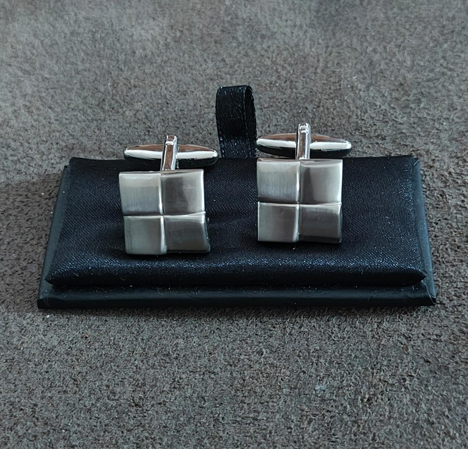 Pair of brushed silver square cuff links with geometric grid styling on black card