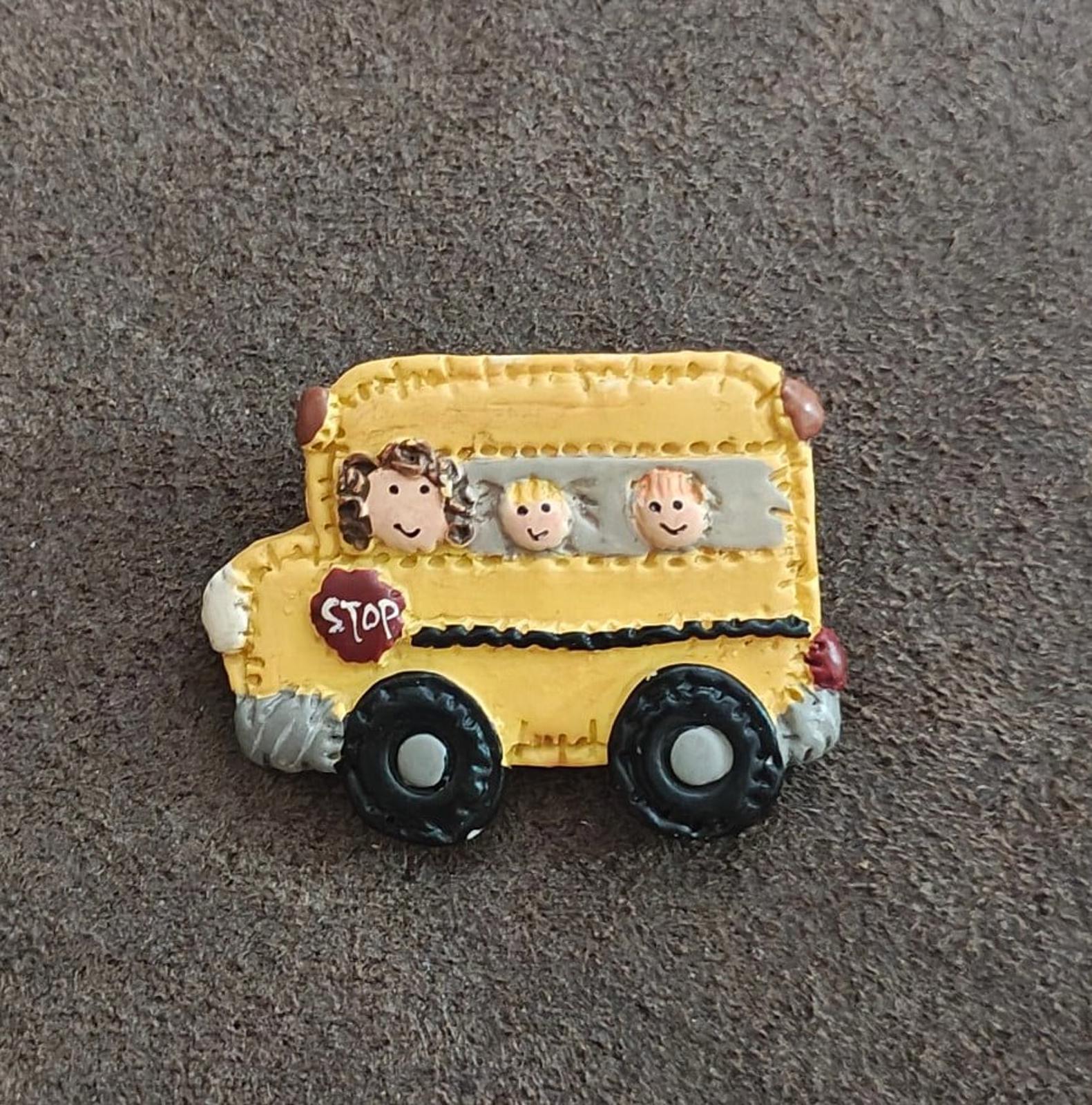 Yellow school bus resin pin with three cartoon faces in window and red STOP sign