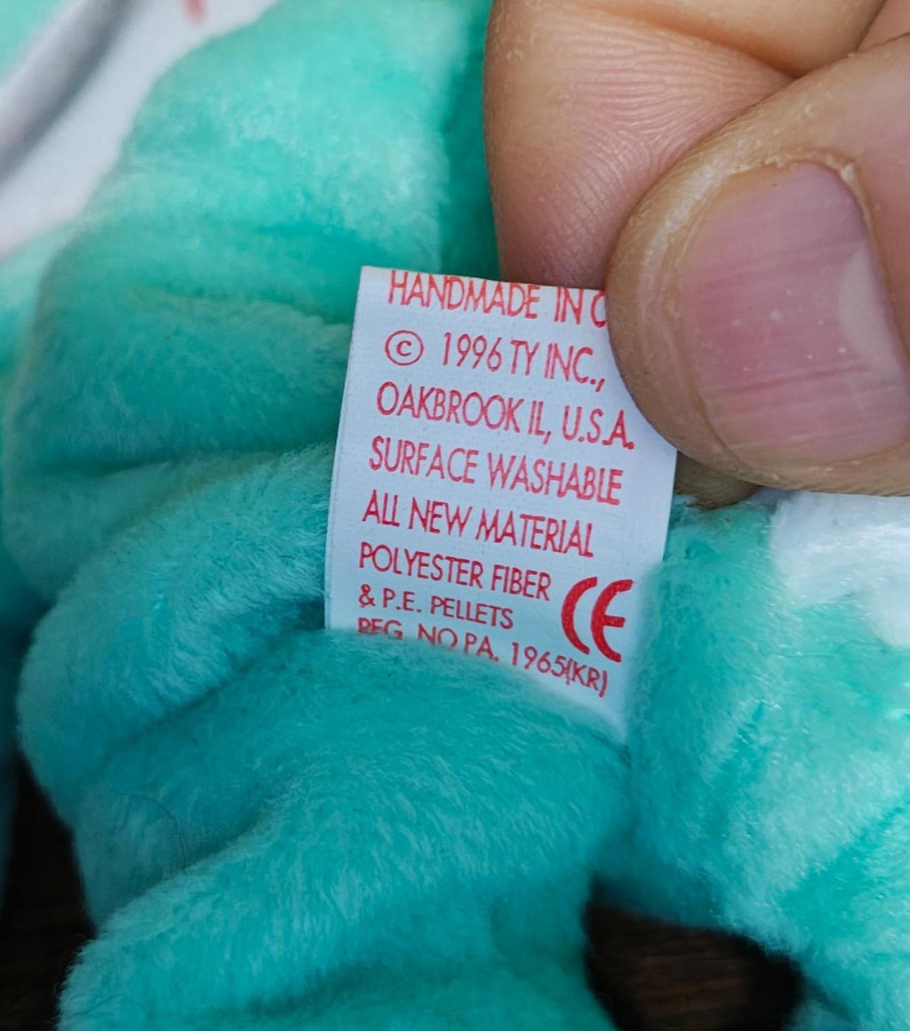 Teal plush bunny care label tag with text including 1996 TY INC and surface washable