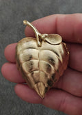 Gold tone leaf-shaped locket brooch with hinged frame and textured brushed detail