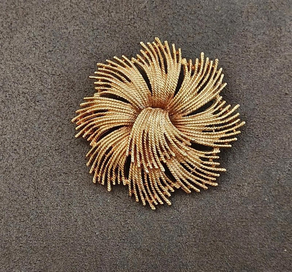Gold-tone starburst rope brooch with spiral-like twisted rays and central coil