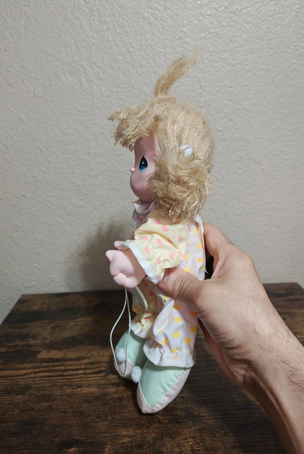 Beige plush friendship doll side view with curly yarn hair and heart-print jacket