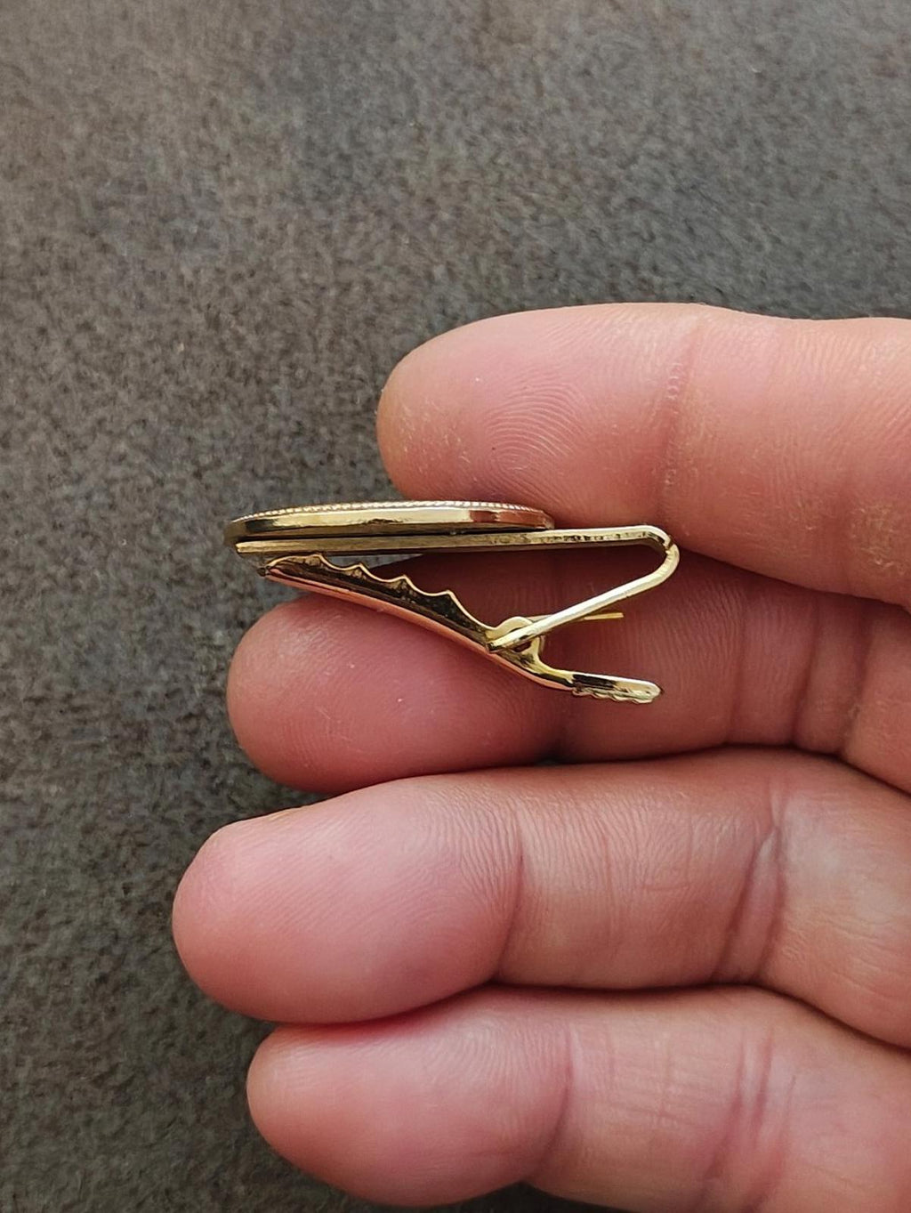 Gold-tone tie clip side view with prong clasp and hinge detail