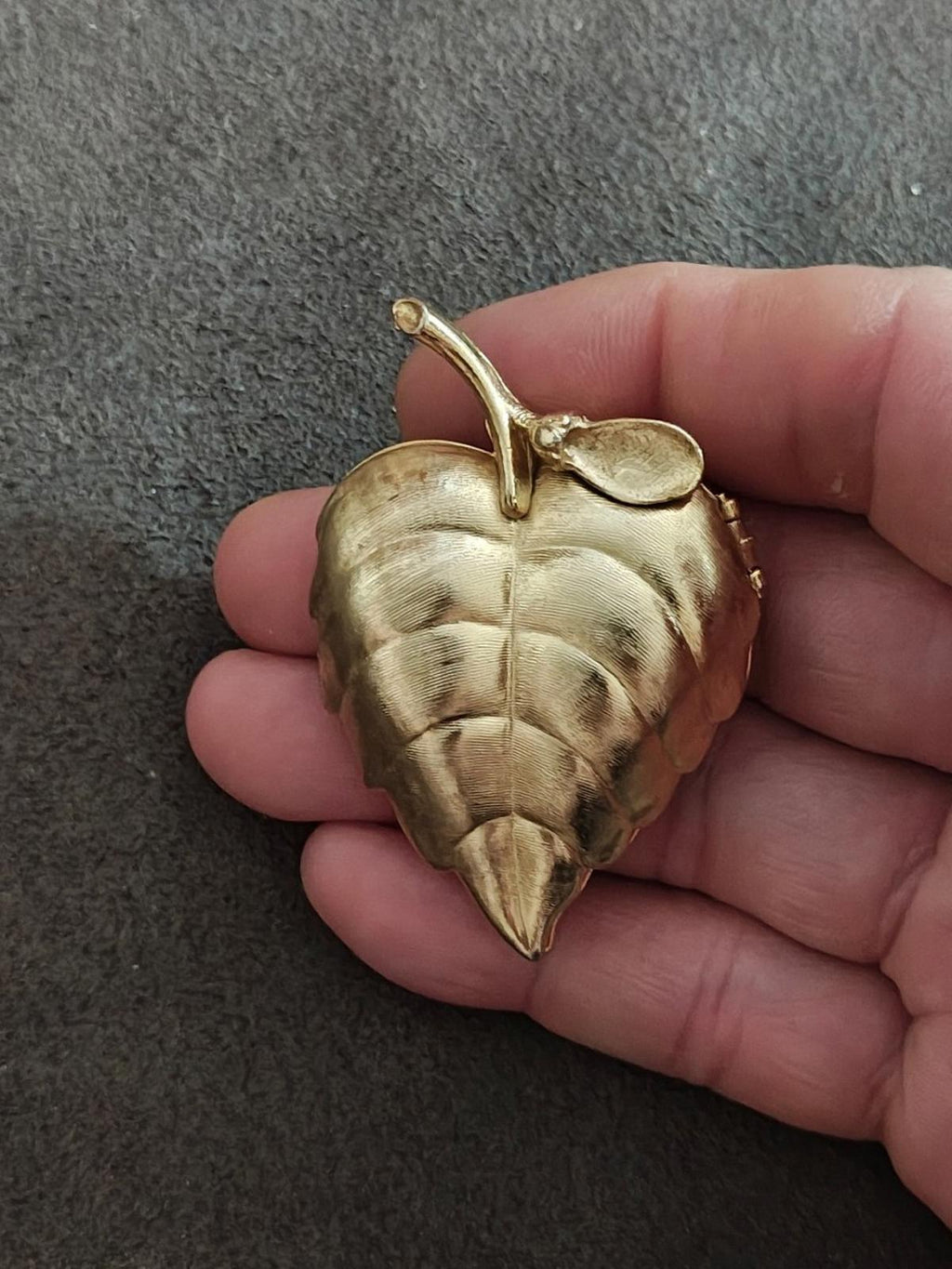 Gold tone leaf locket brooch with brushed finish and hinged clasp detail on edge