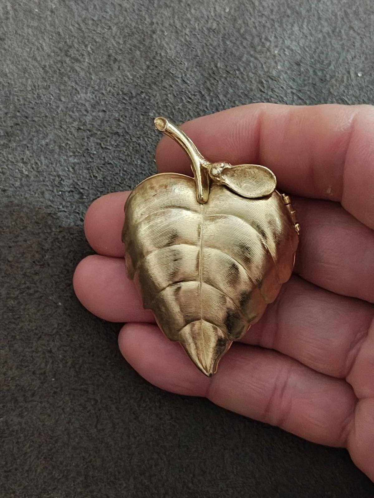 Gold tone leaf locket brooch with brushed finish and hinged clasp detail on edge