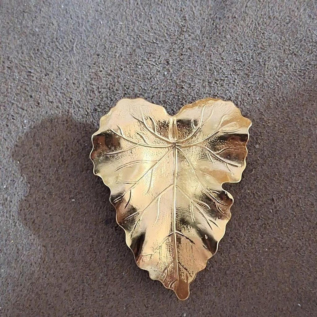 Gold-tone textured leaf scarf clip with central stem vein design, flat view