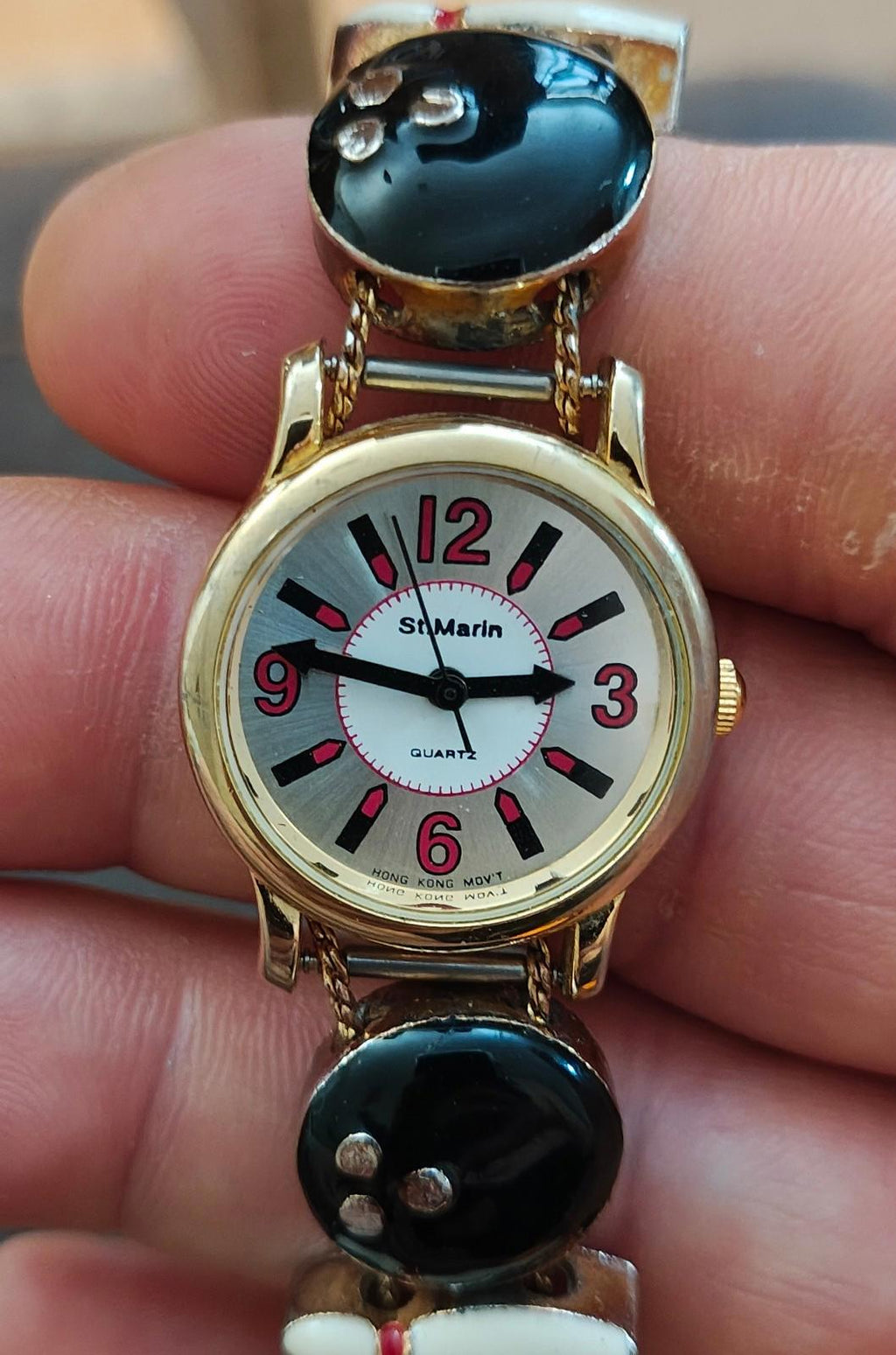 Ladies novelty watch with gold-tone round case, white dial, black top, red accents
