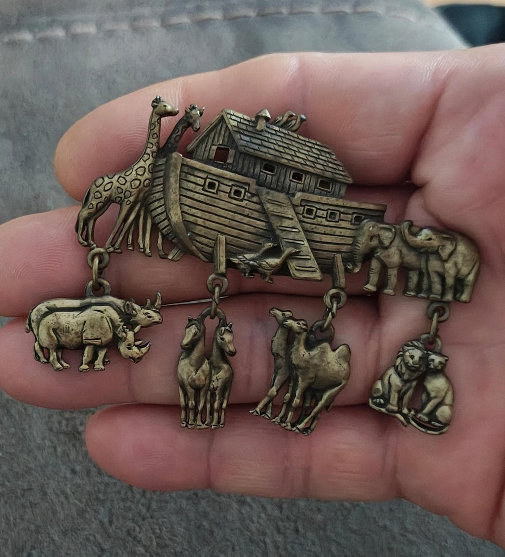 Gold Noah’s Ark dangle brooch pin held in hand with animal charms and ark details