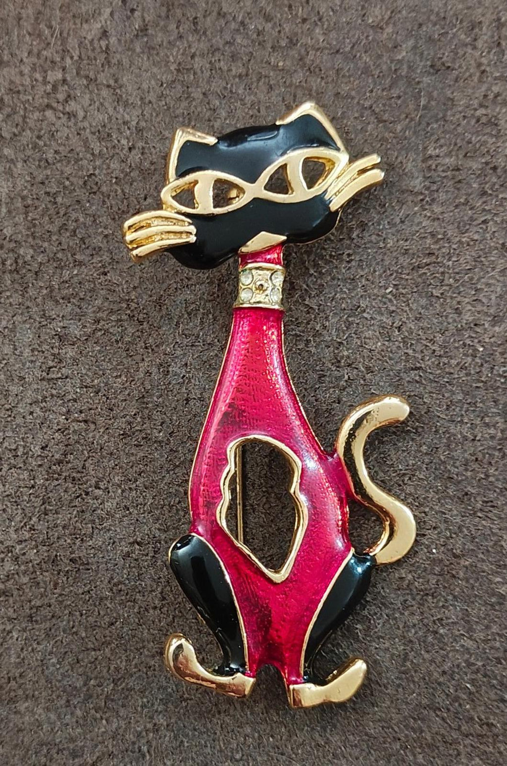 Red and black enamel cat mask brooch with gold-tone detailing, straight-on view.