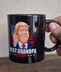 Black ceramic mug with illustrated man portrait and text “Best Grandpa Ever”.