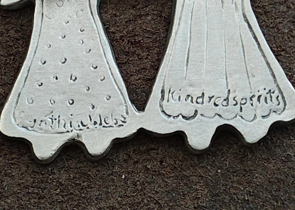 Close-up of engraved text on silver-tone pin back: Kindred Spirits