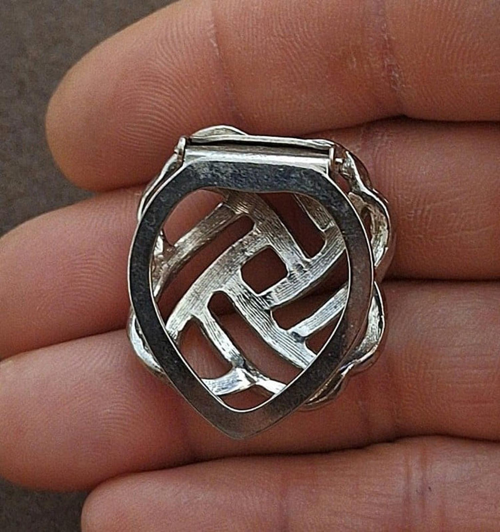 Silver scarf clip back with lattice cutout and hinge clasp, held in fingers