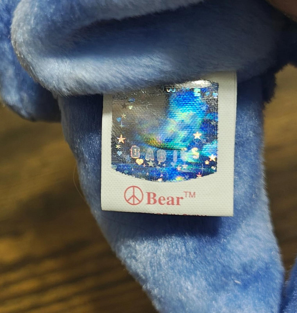 Blue bear plush side view with Beanie Bear tag label and colorful image graphic