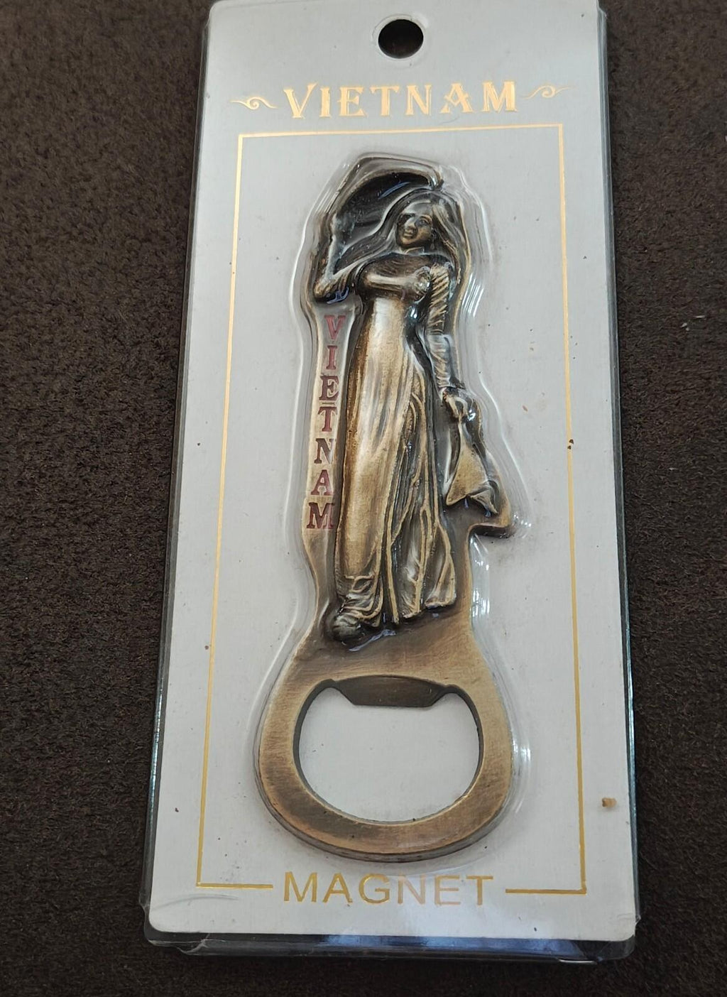 Brass magnetic bottle opener souvenir showing a standing woman holding a bag, cap opening.