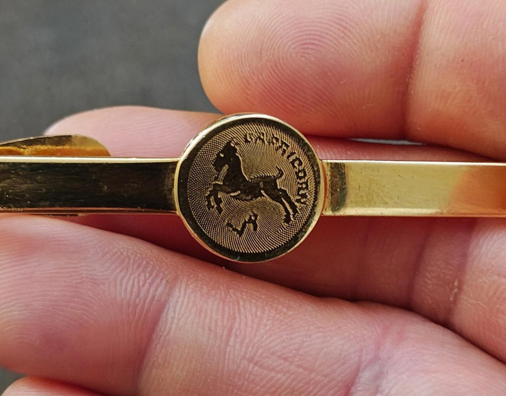 Gold-tone Capricorn zodiac tie bar in hand with round front medallion
