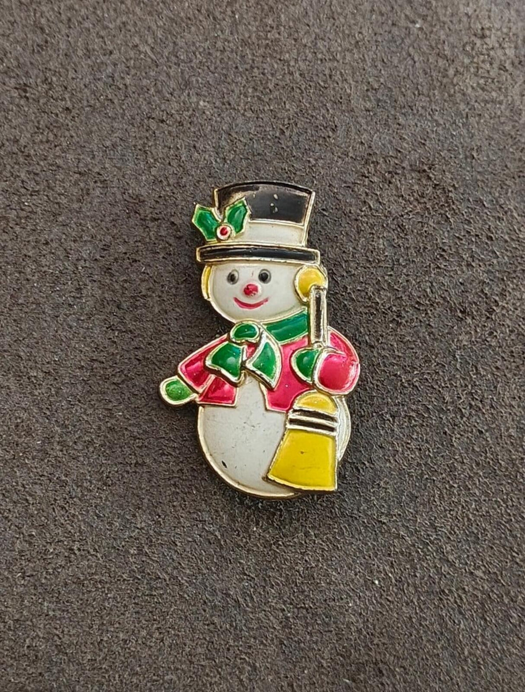 Enamel snowman brooch with green hat and red ornament, holding yellow lantern
