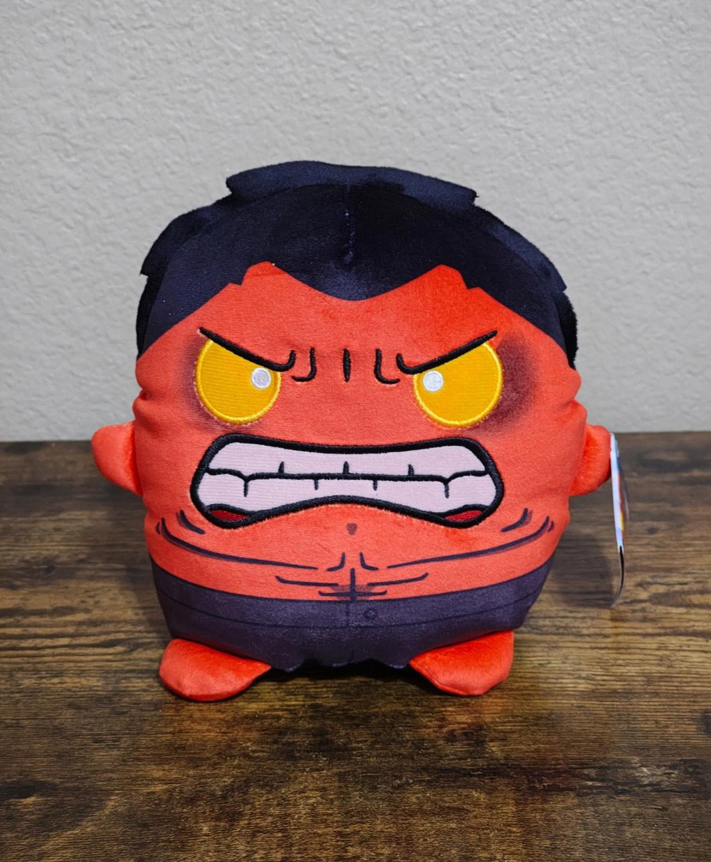Front view red and navy plush character with yellow eyes and grimacing mouth