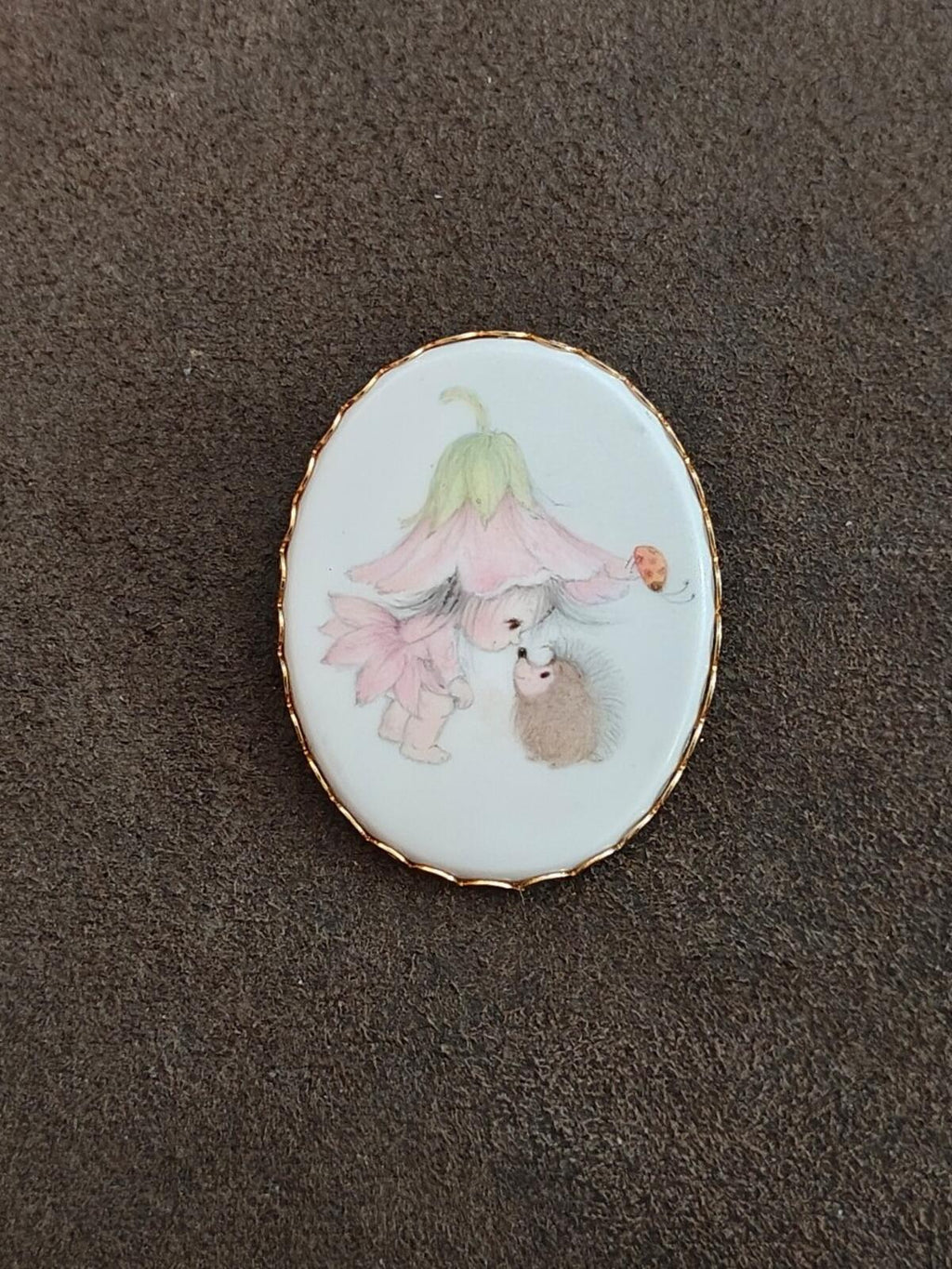 Oval gold-tone enamel cameo brooch showing painted pixie girl and bunny-like figure