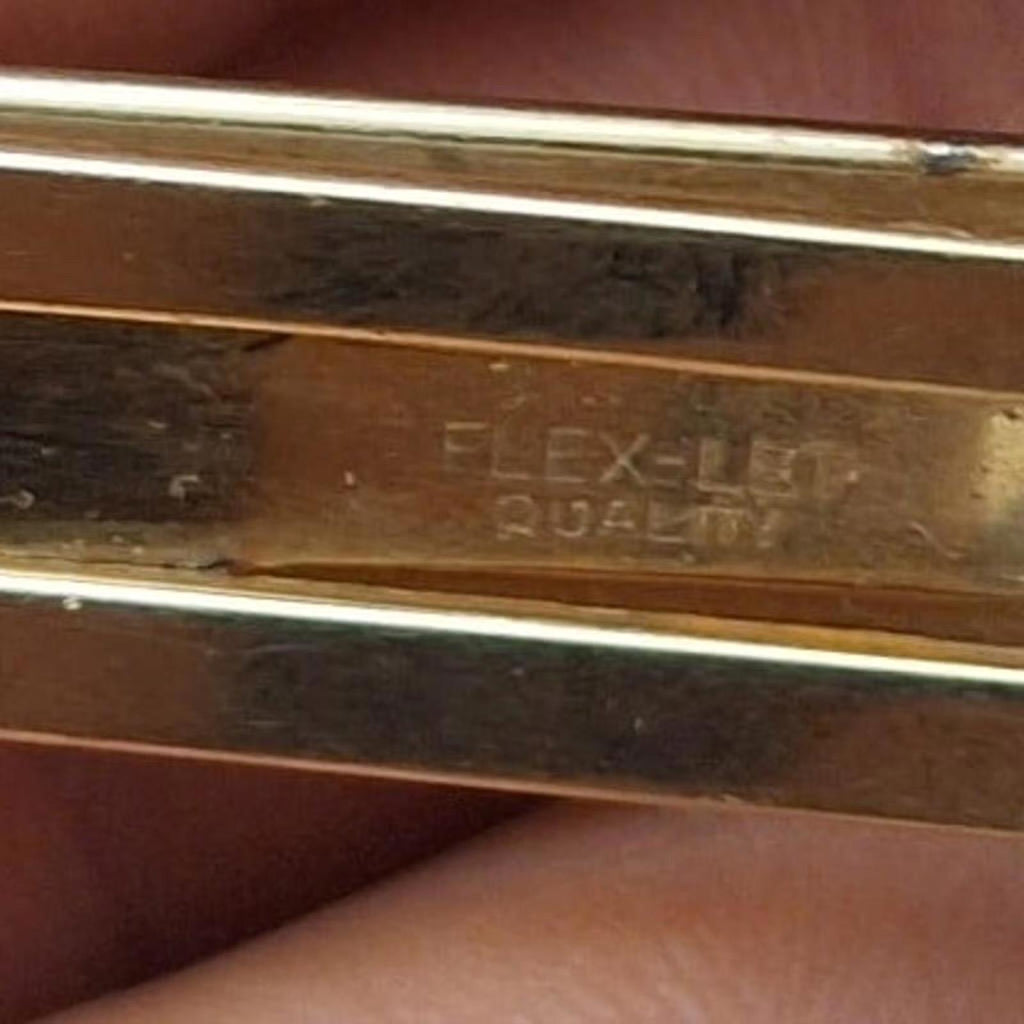Gold tone tie bar clip back close-up with engraved text and bars