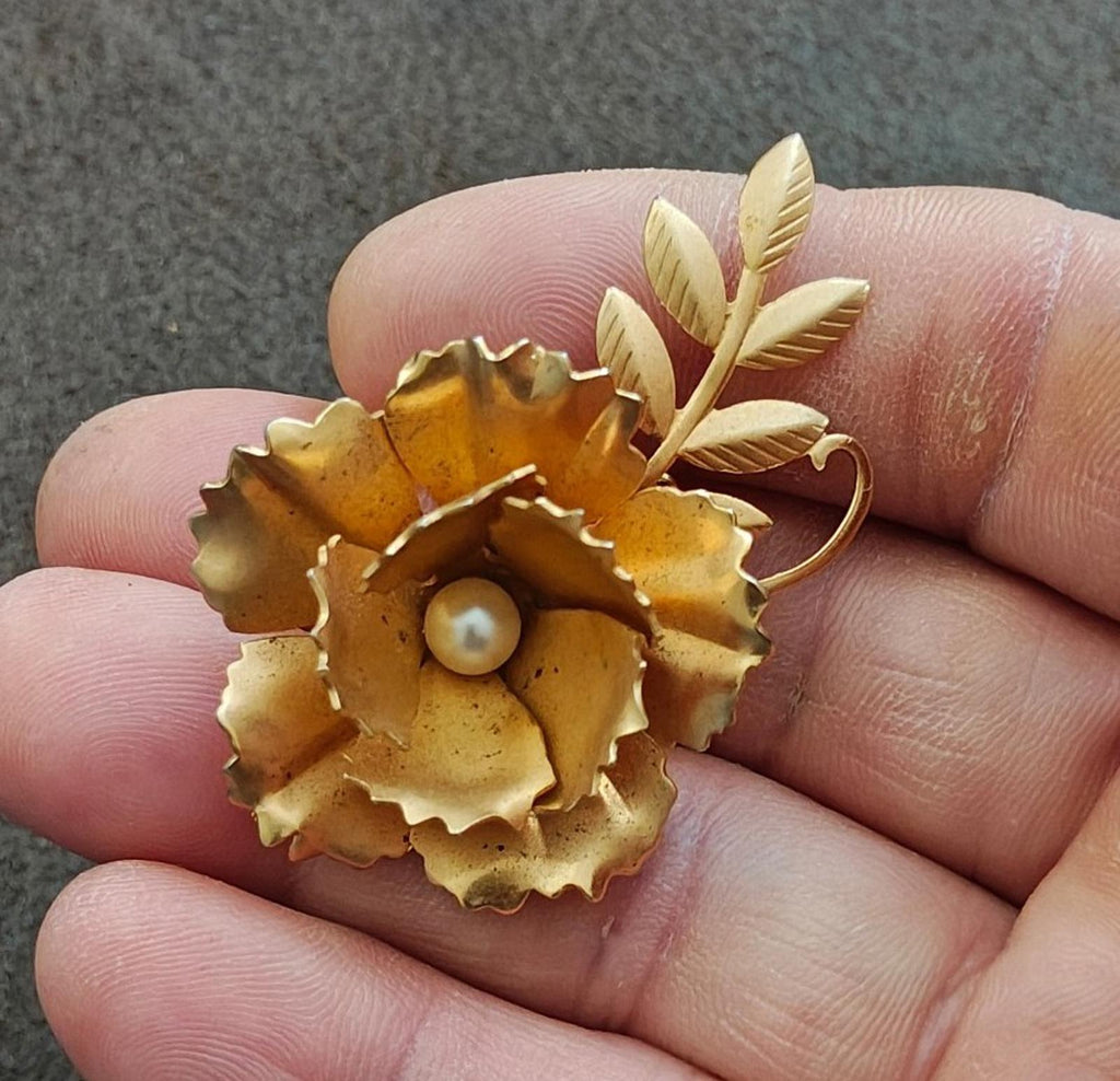 Gold-tone floral brooch with faux pearl center and leaf stem details