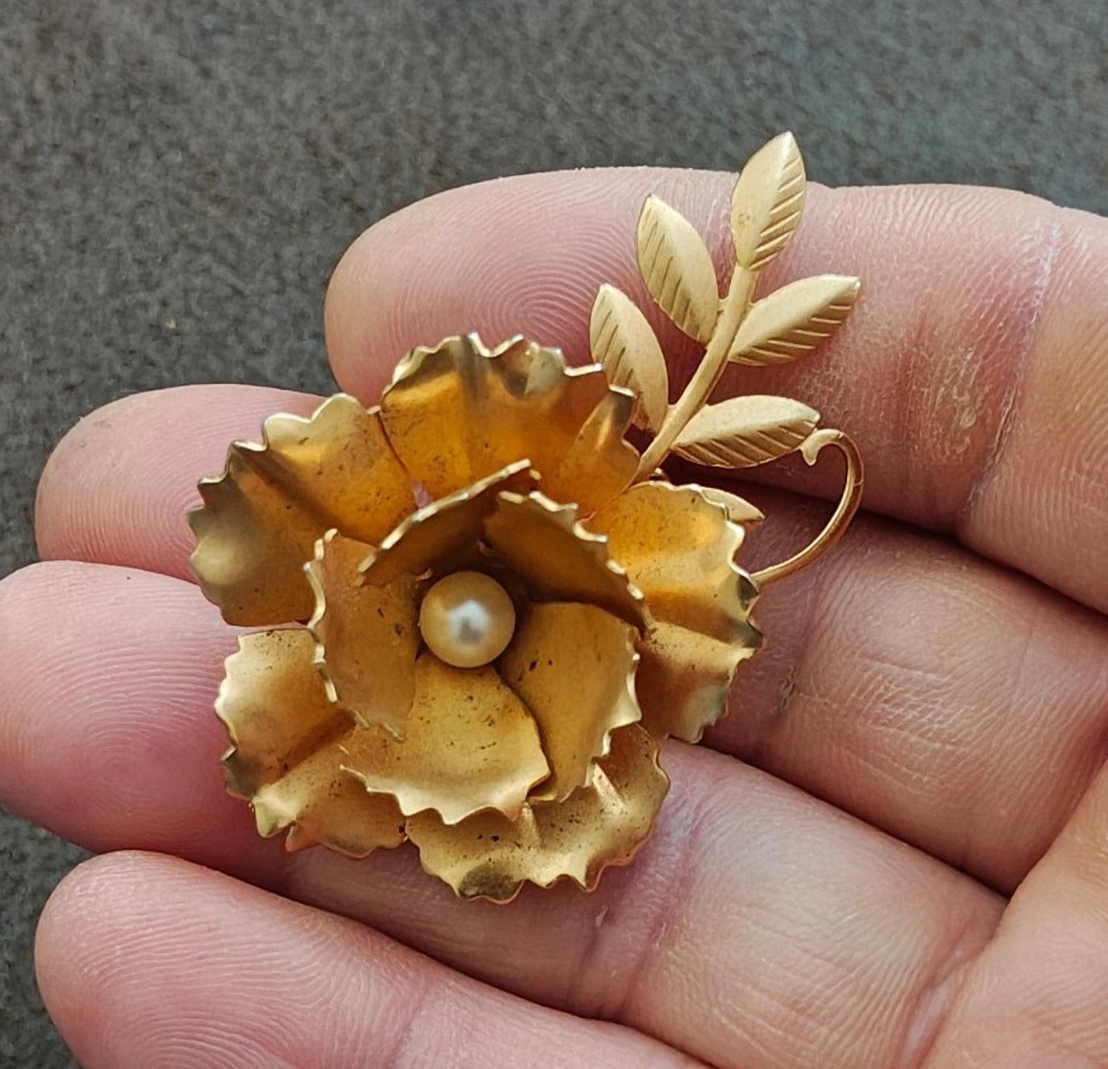 Gold-tone floral brooch with faux pearl center and leaf stem details