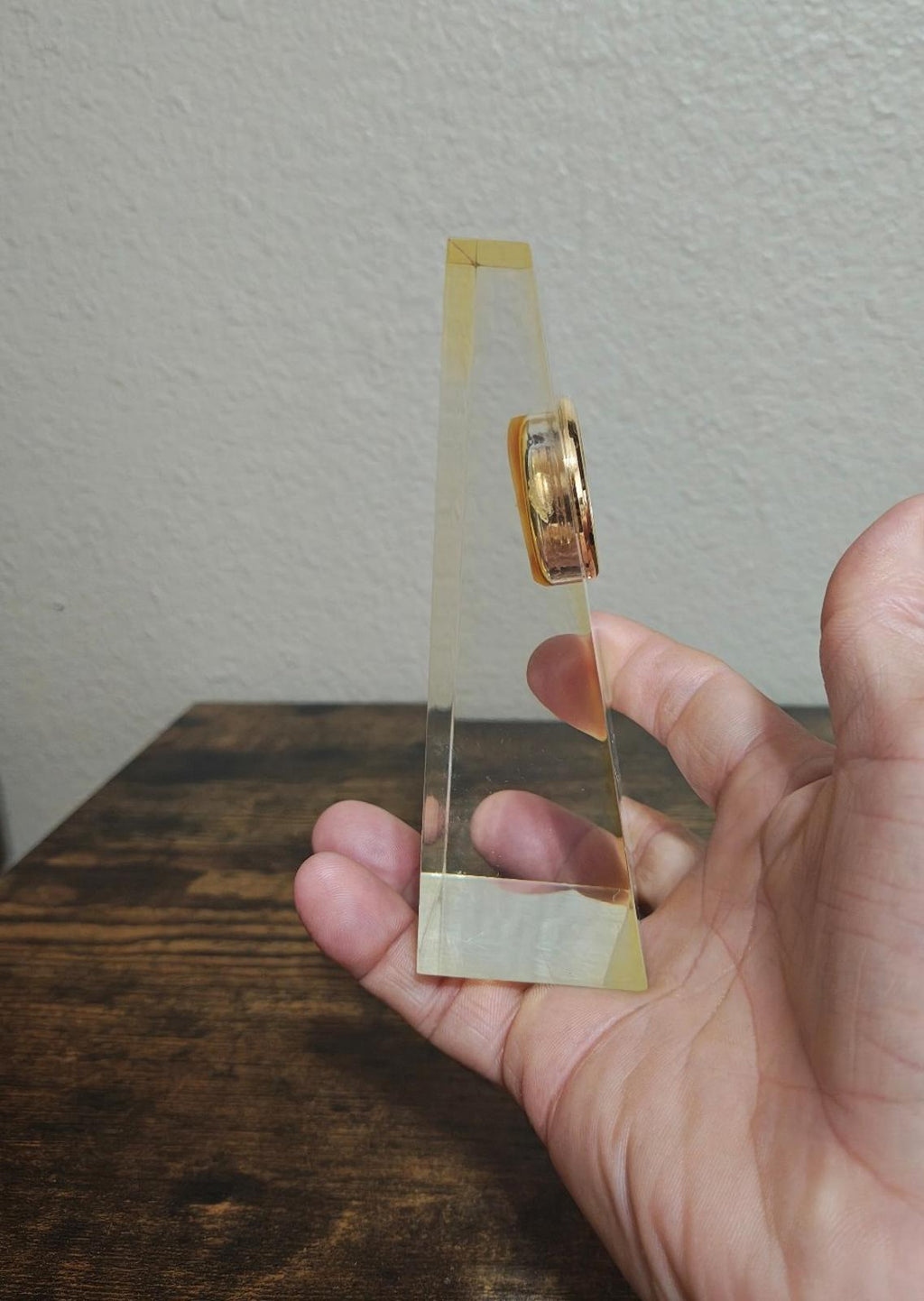 Clear acrylic desk clock with gold bezel, narrow side profile of the clear stand