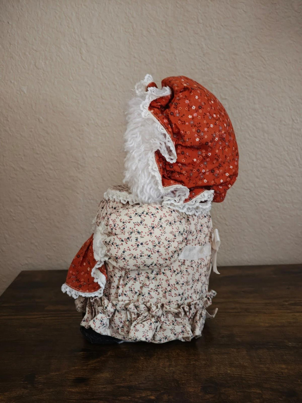 Handmade cloth doll canister from the back, red bonnet and white floral dress with ruffles.