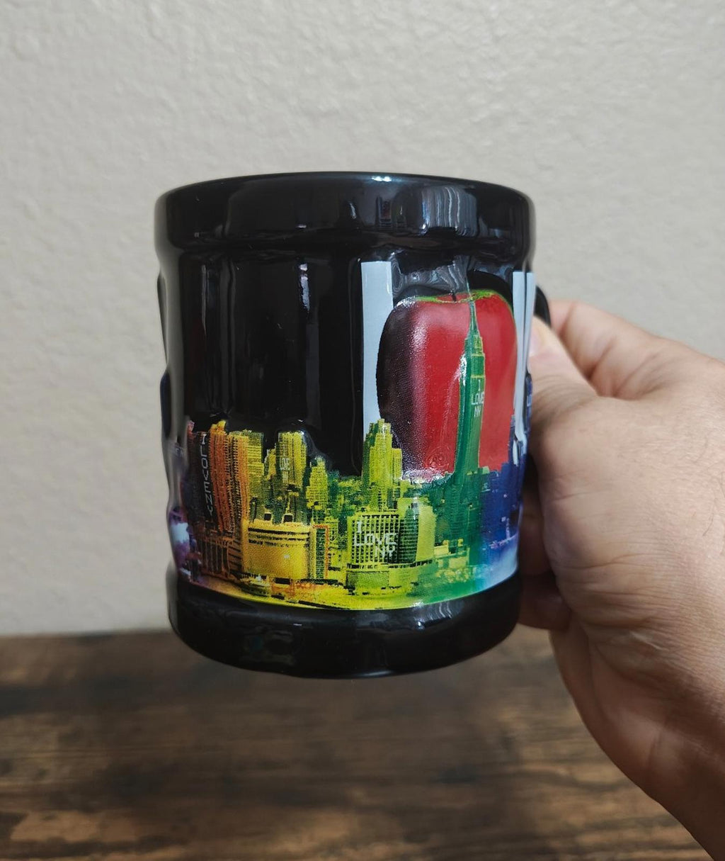 Black ceramic mug with colorful skyline graphic, glossy glaze, side angle