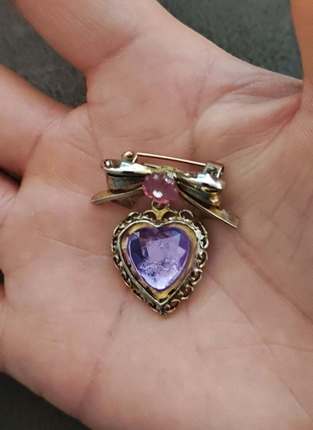 Gold-tone bow brooch featuring purple heart stone and pink flower center charm