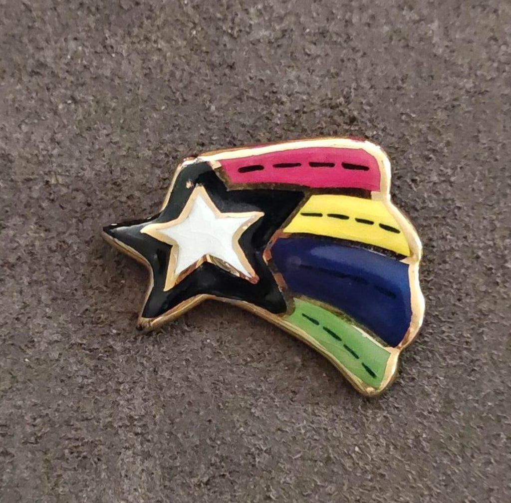 Glazed ceramic shooting star pin brooch, angled view with rainbow stripes and white star