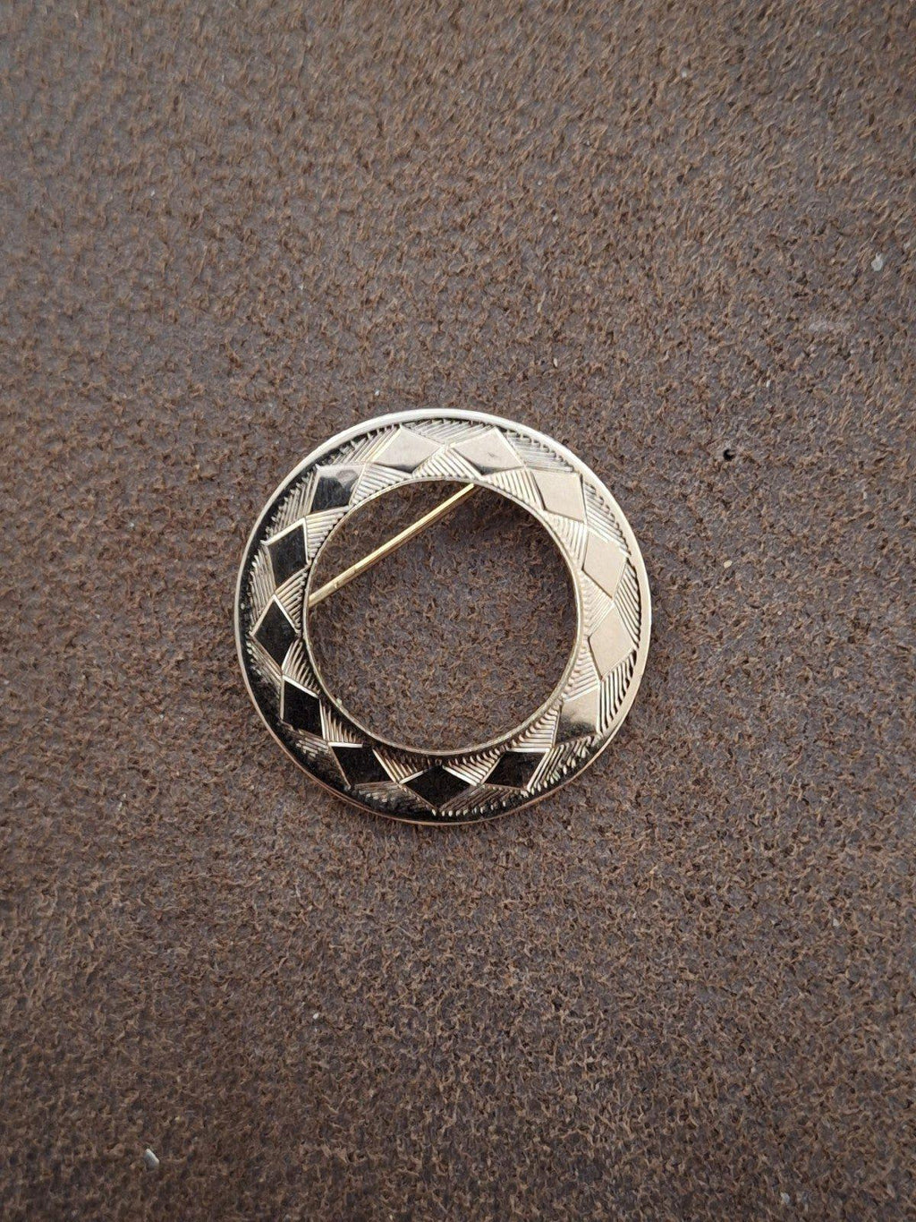 Goldtone circle pin brooch with high-contrast etched chevrons and diamond pattern