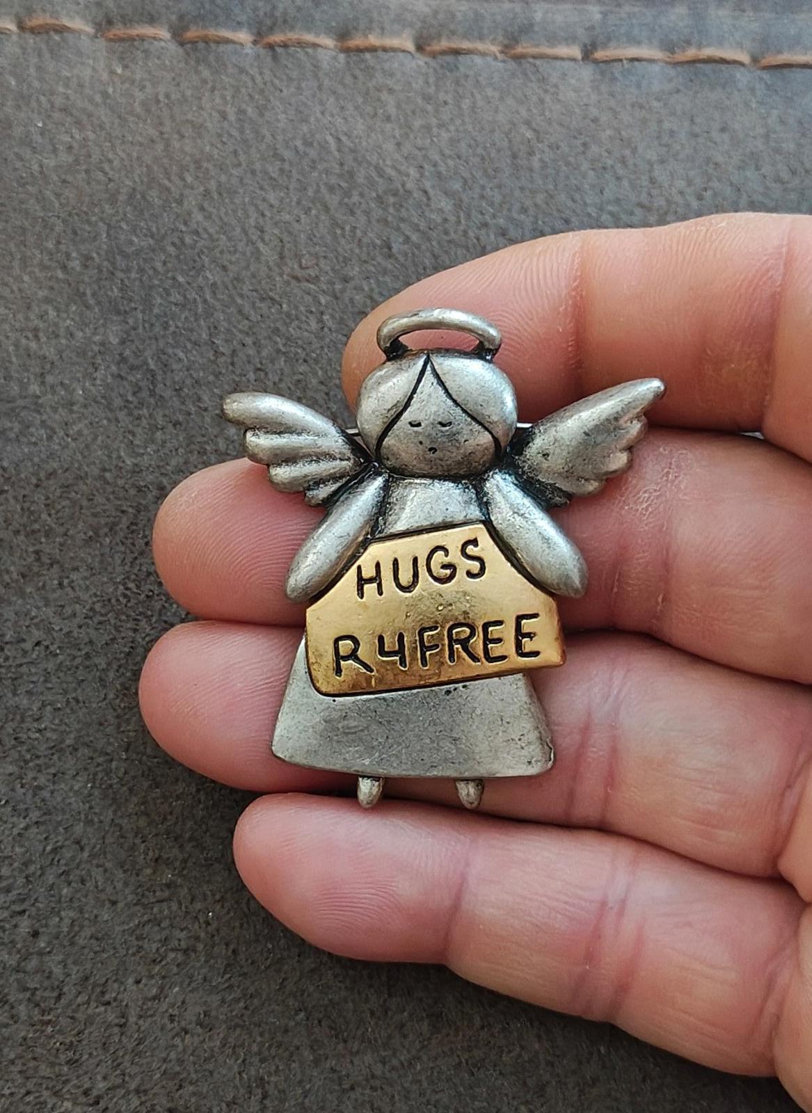 Silver angel pin brooch with tan sign reading HUGS R4FREE and spread wings