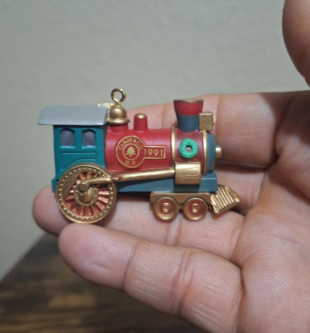 Blue and red train locomotive ornament with red badge, gold smokestack, and hanging loop